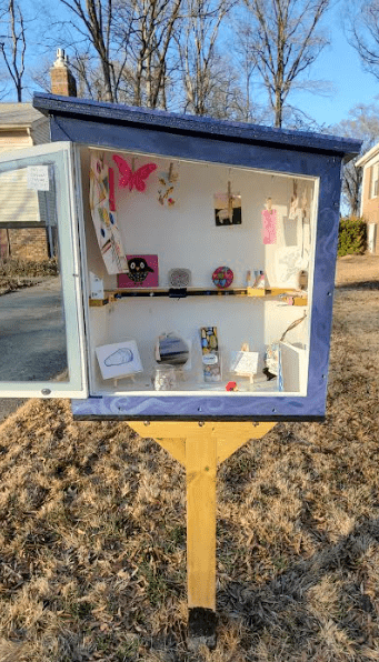 A wooden box showcasing local art in front of a home in Mount Vernon District.