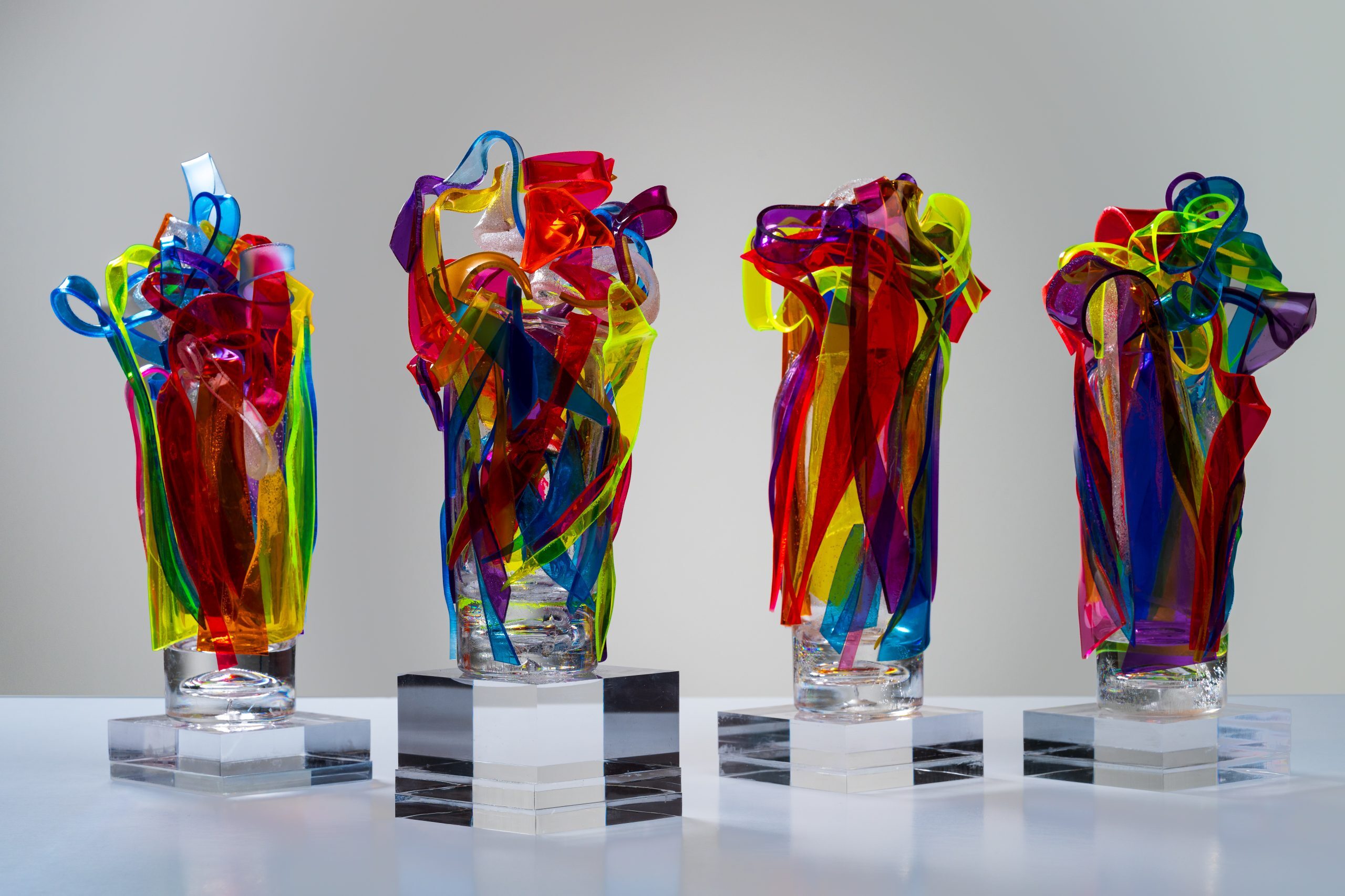 a photo of four colorful tabletop sculptures featuring ribbons of twisted fiberglass material.